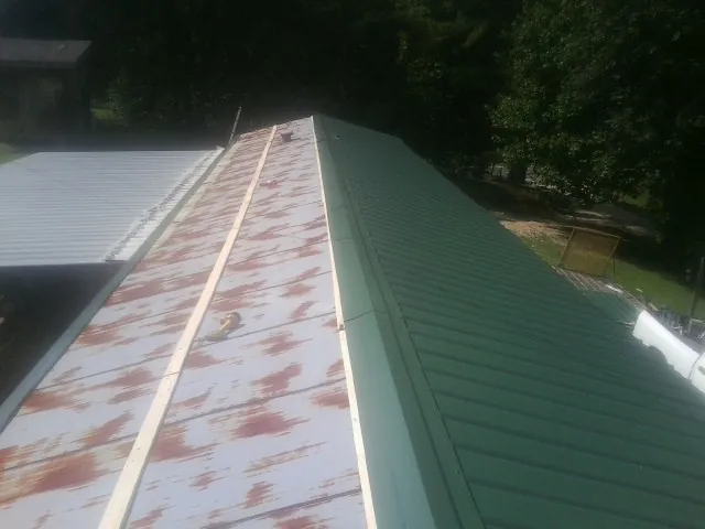 Old rusted panels beside newly installed green metal roofing — Wind Damage Roof Repair by Roofing Brothers in Nebo