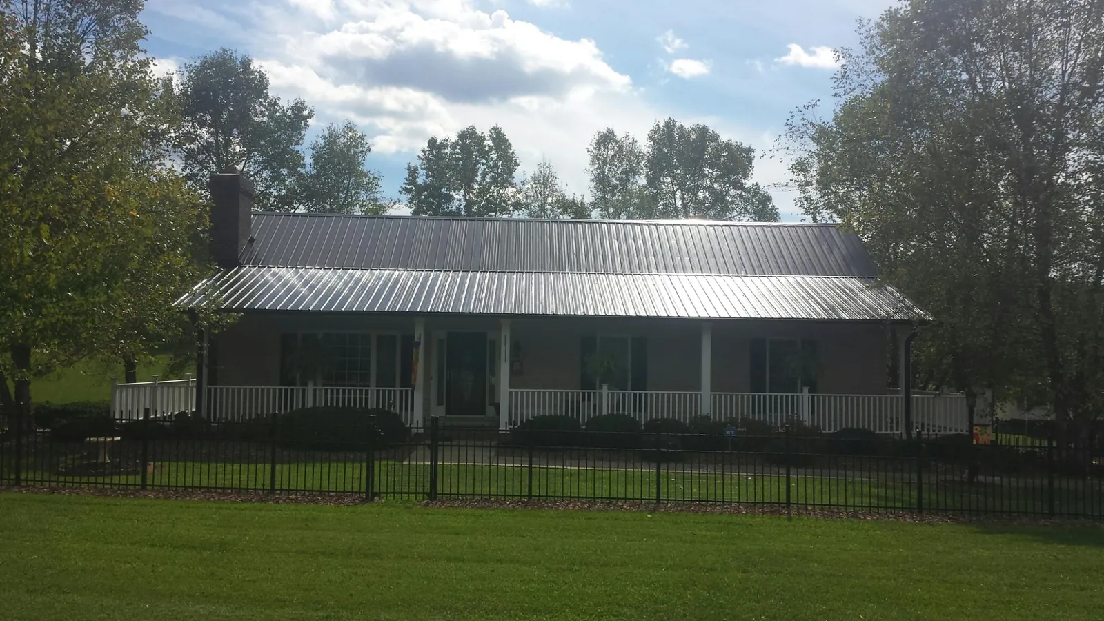 Gray metal roof on a brick ranch with a full width front porch — Gutter Guard Installation work by our crew in Nebo