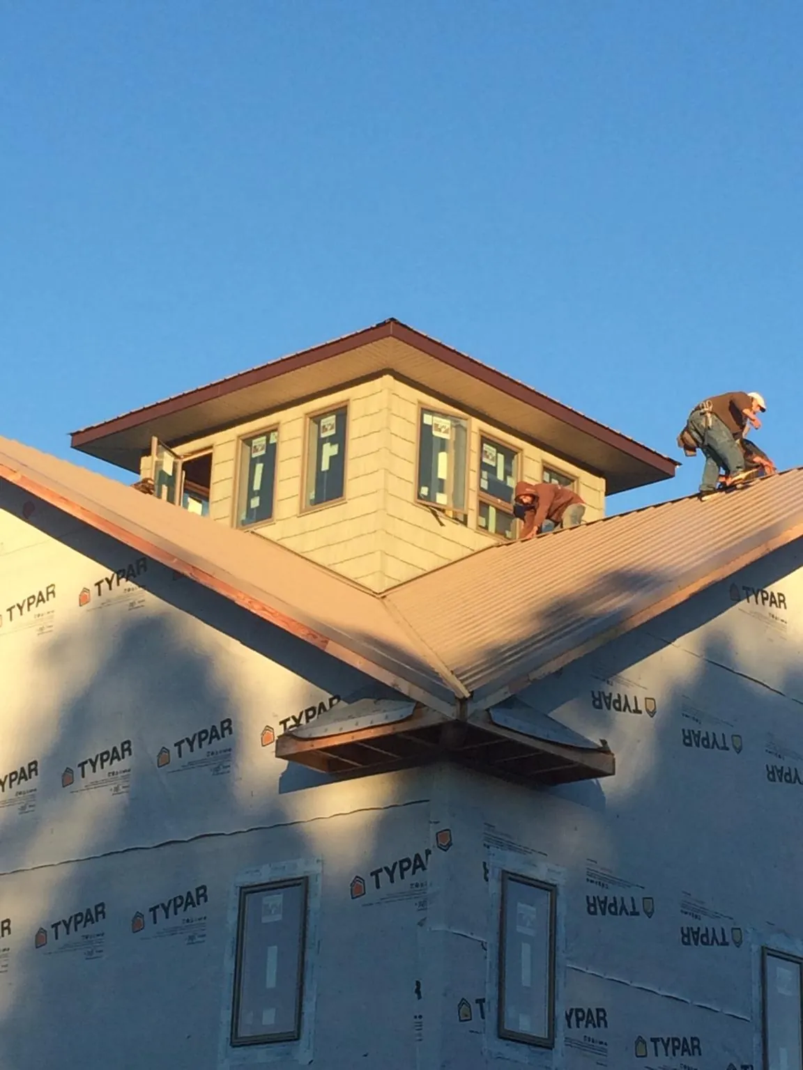 Roofers working around a rooftop cupola on a new metal roof at sunset — Roof Waterproofing in Nebo by Roofing Brothers